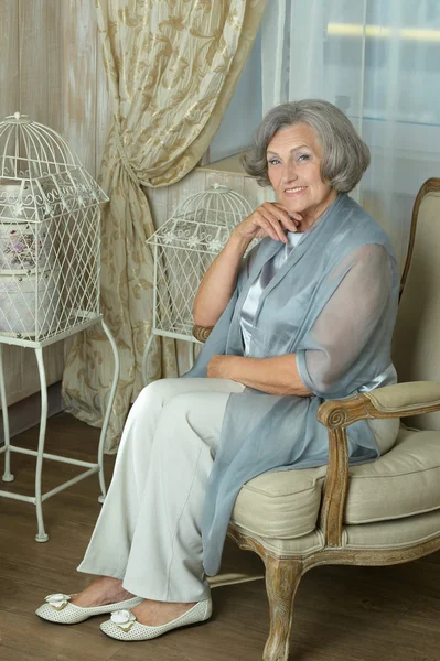 Mature woman sitting in vintage sofa — Stock Photo, Image