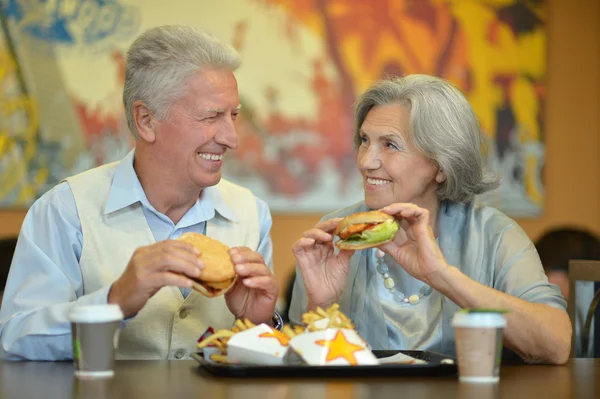 Pareja mayor comiendo comida rápida — Foto de Stock