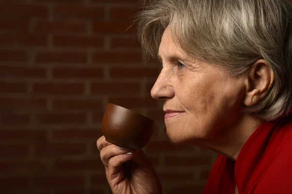 Starsza kobieta czerwony, picia kawy — Zdjęcie stockowe