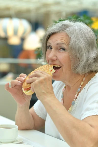 Oudere vrouw eten fastfood — Stockfoto