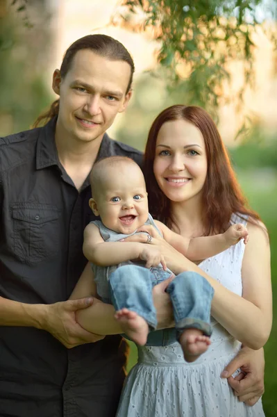 Feliz familia sosteniendo hijo en el parque — Foto de Stock