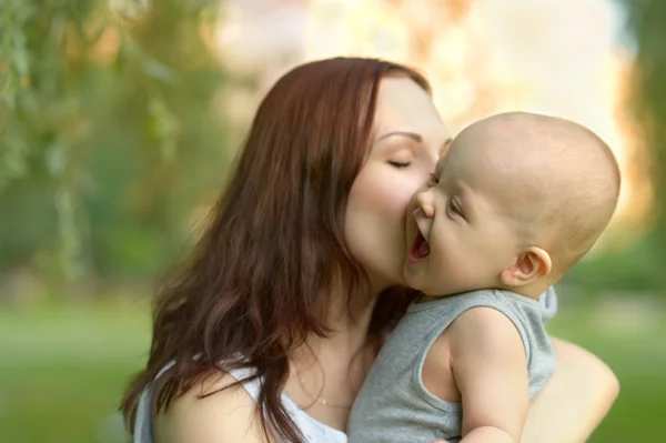 Mãe segurando um jovem filho no parque — Fotografia de Stock