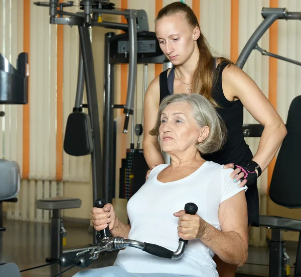 Mujer haciendo ejercicio en el gimnasio con entrenador deportivo —  Fotos de Stock