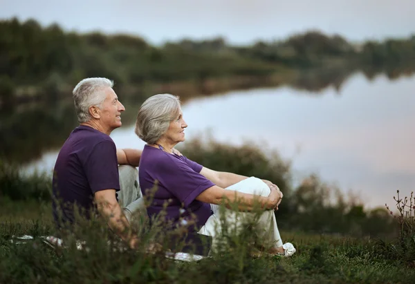 Senior koppel zitten in de buurt van nabij lake — Stockfoto