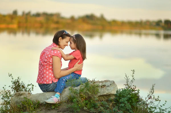 Niña abrazando a su madre cerca del lago —  Fotos de Stock