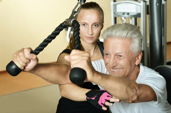 Man exercising in gym with trainer