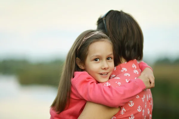 Bambina che abbraccia sua madre vicino al lago — Foto Stock