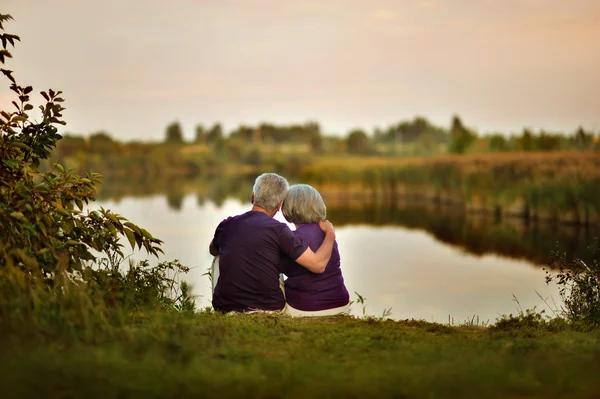 Äldre par sitter nära lake — Stockfoto