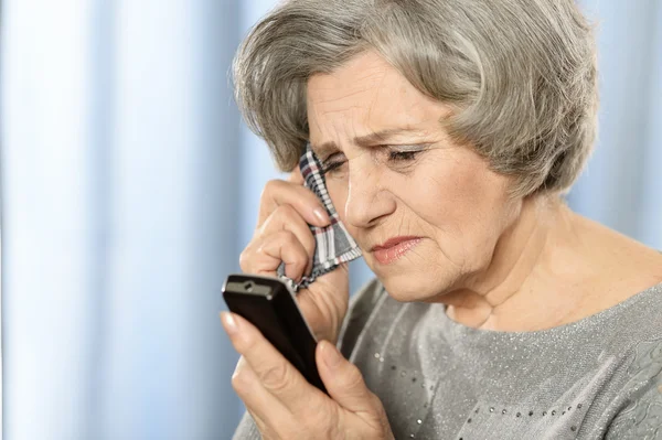 Pensive elderly woman calling on the phone — Stock Photo, Image