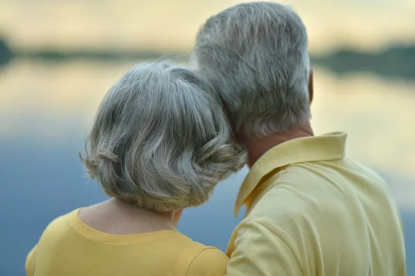Старша пара сидить біля озера — стокове фото