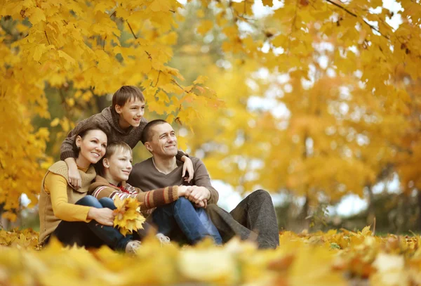 Rodzina siedzi w jesiennym parku — Zdjęcie stockowe
