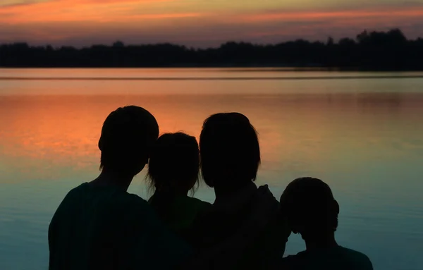 Família perto do rio contra o pôr do sol — Fotografia de Stock