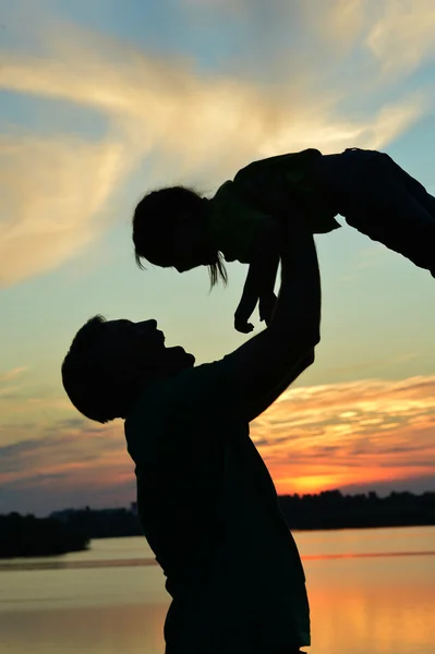 Dad holding daughter against the sunset — Stock Photo, Image