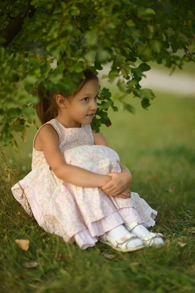 Little girl sitting under a tree — Stock Photo, Image