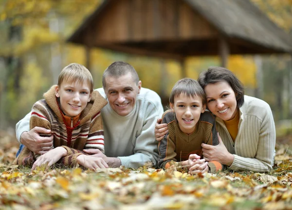 Happy family lying in autumn park — Stock Photo, Image