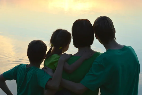 Familjen nära floden mot solnedgången — Stockfoto