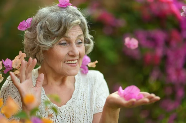 Äldre kvinna med blommor — Stockfoto