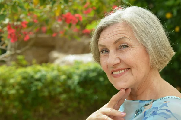 Ältere Frau mit roten Blumen — Stockfoto