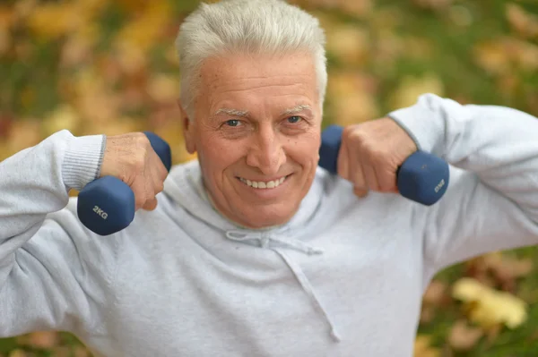 Elderly man exercising with dumbbells — Stock Photo, Image