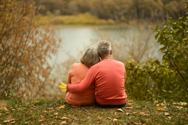 Mature couple sitting near lake — Stock Photo, Image