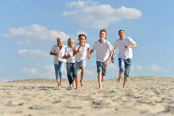 Família feliz correndo em uma praia — Fotografia de Stock