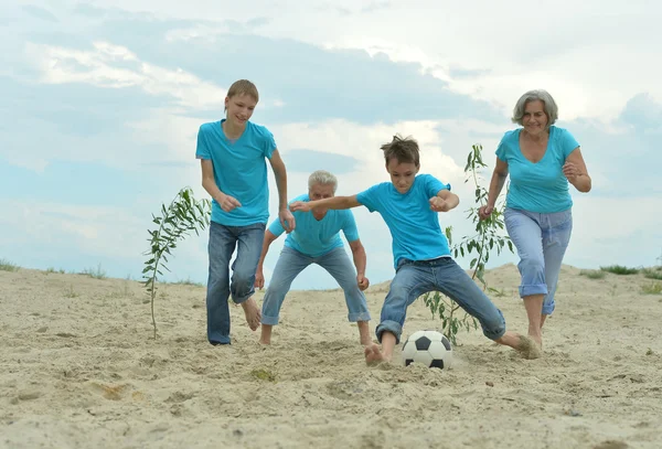 Familj spelar fotboll på en strand — Stockfoto