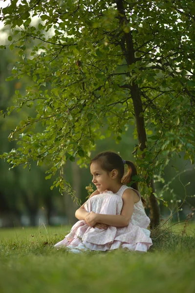 Petite fille assise sous un arbre — Photo