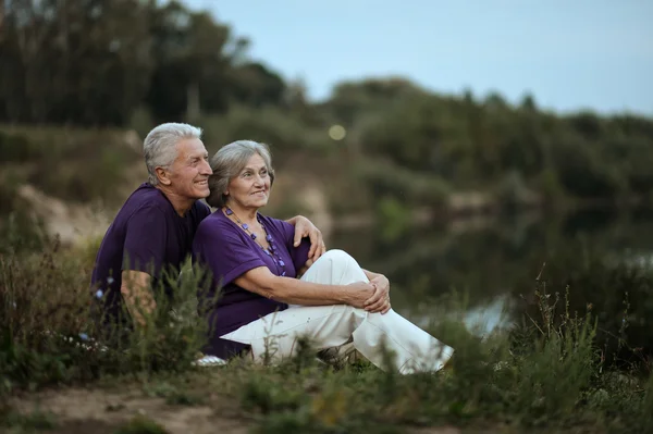 Mature couple sitting near lake — Stock Photo, Image