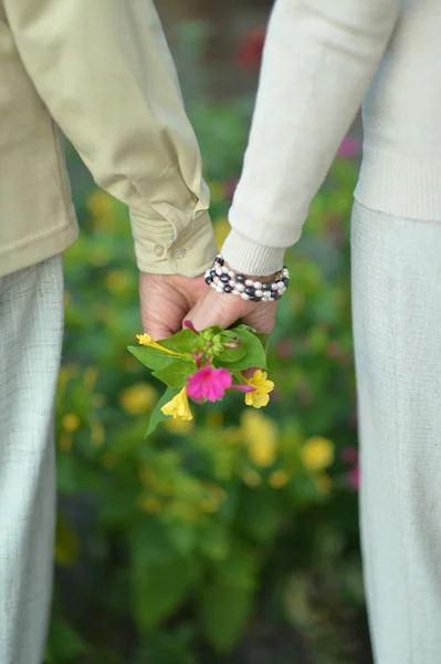 Pareja cogida de la mano con flores —  Fotos de Stock