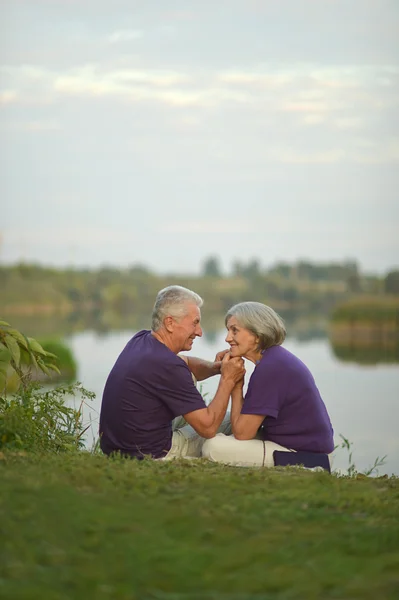 成熟的夫妇坐在靠近湖 — 图库照片