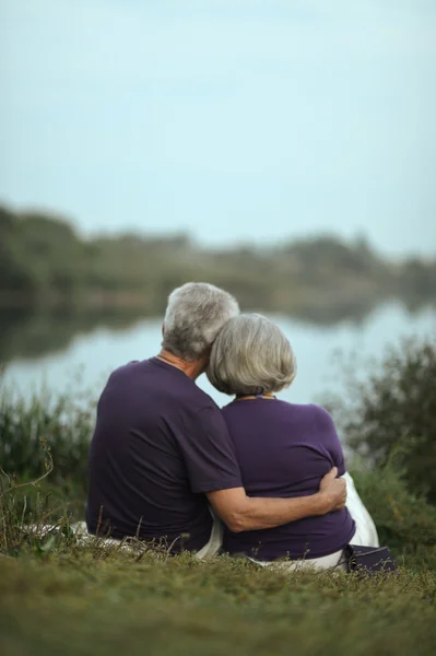 Зрелая пара, сидящая у озера — стоковое фото