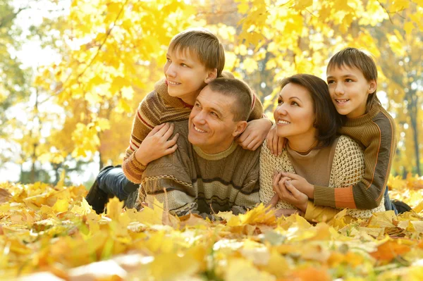 Happy family lying in autumn park — Stock Photo, Image
