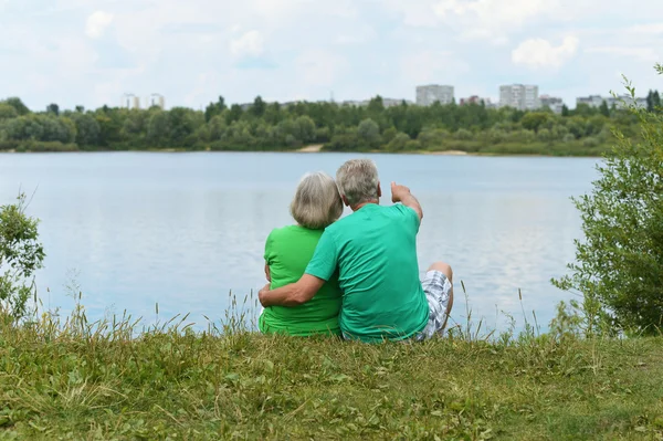 Couple âgé assis près du lac — Photo