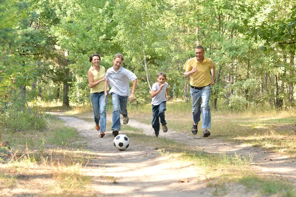 Familj spelar fotboll i skogen — Stockfoto