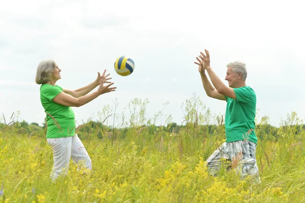 Senior couple in field with ball — Stock Photo, Image