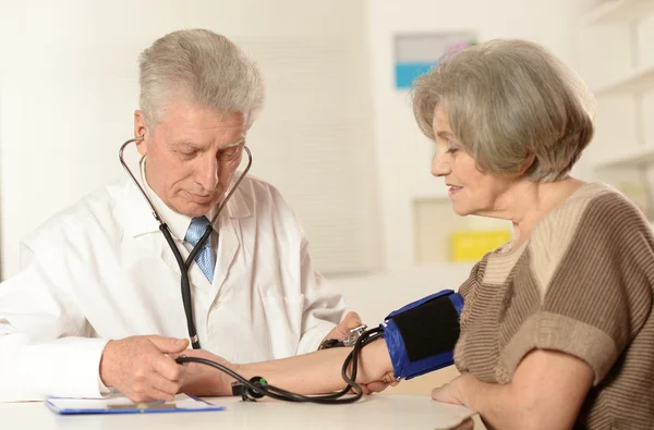 Médico midiendo la presión arterial de la mujer — Foto de Stock