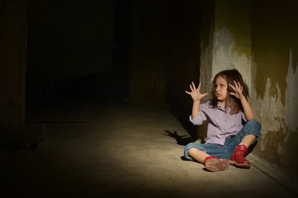 Ensam liten flicka i en mörk källare — Stockfoto