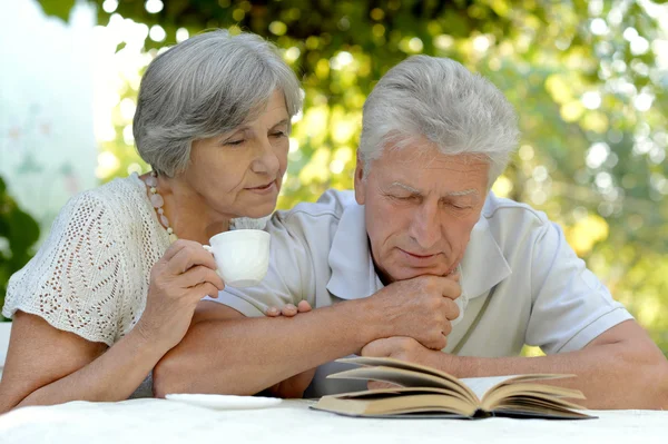 Old couple with  drink and book — Stock Photo, Image