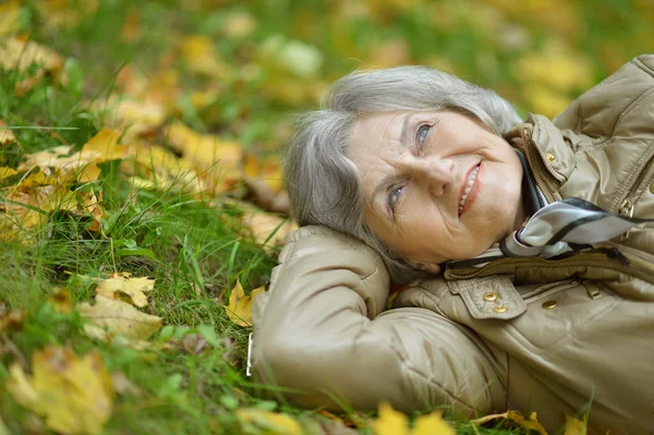 Donna anziana sdraiata sulle foglie — Foto Stock