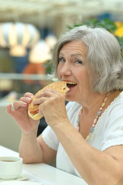 Seniorin isst Hamburger — Stockfoto