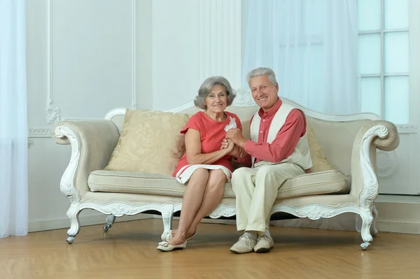 Старшая пара сидит на диване — стоковое фото