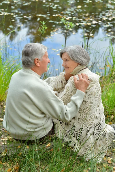 Пожилая пара, сидящая у озера — стоковое фото