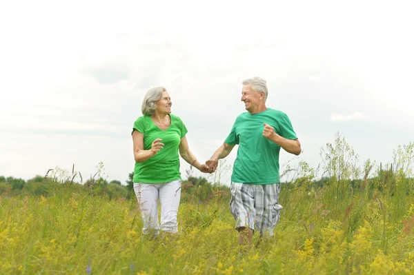 Senior couple running in  field — Stock Photo, Image