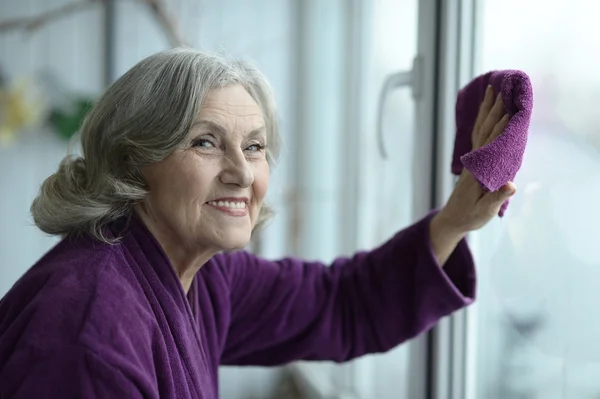 Старшая женщина уборка окна — стоковое фото