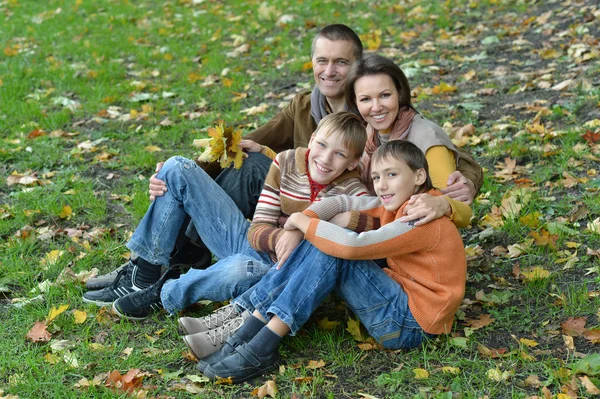 Family sitting in autumn park — Stock Photo, Image