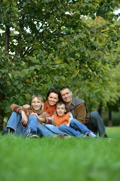 Family sitting in autumn park — Stock Photo, Image