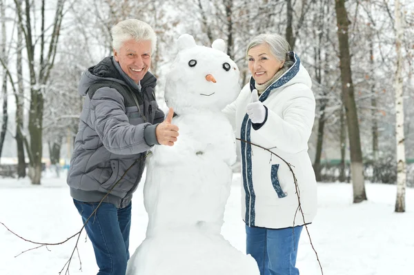 Bejaarde echtpaar maken sneeuwpop — Stockfoto