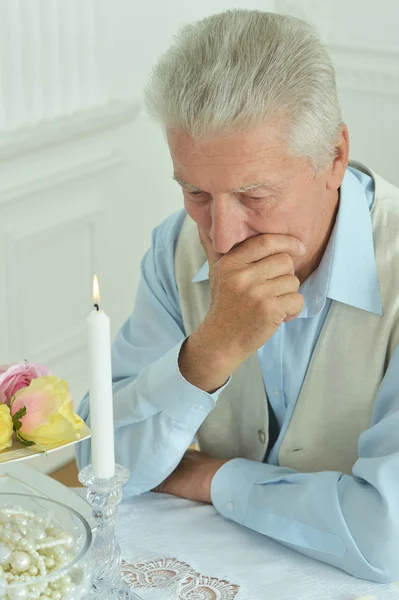 Elderly man sitting on table — Stock Photo, Image