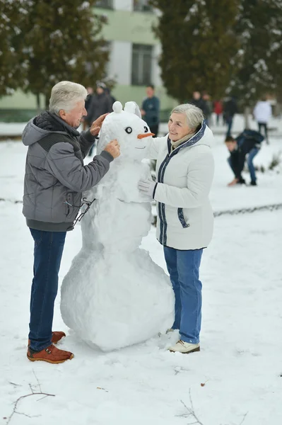 Bejaarde echtpaar maken sneeuwpop — Stockfoto