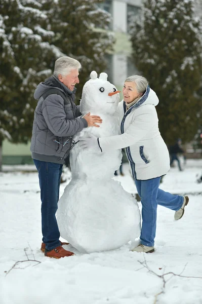 Bejaarde echtpaar maken sneeuwpop — Stockfoto